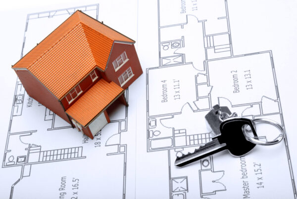 A model home and house key on architectural floor plans for an extension